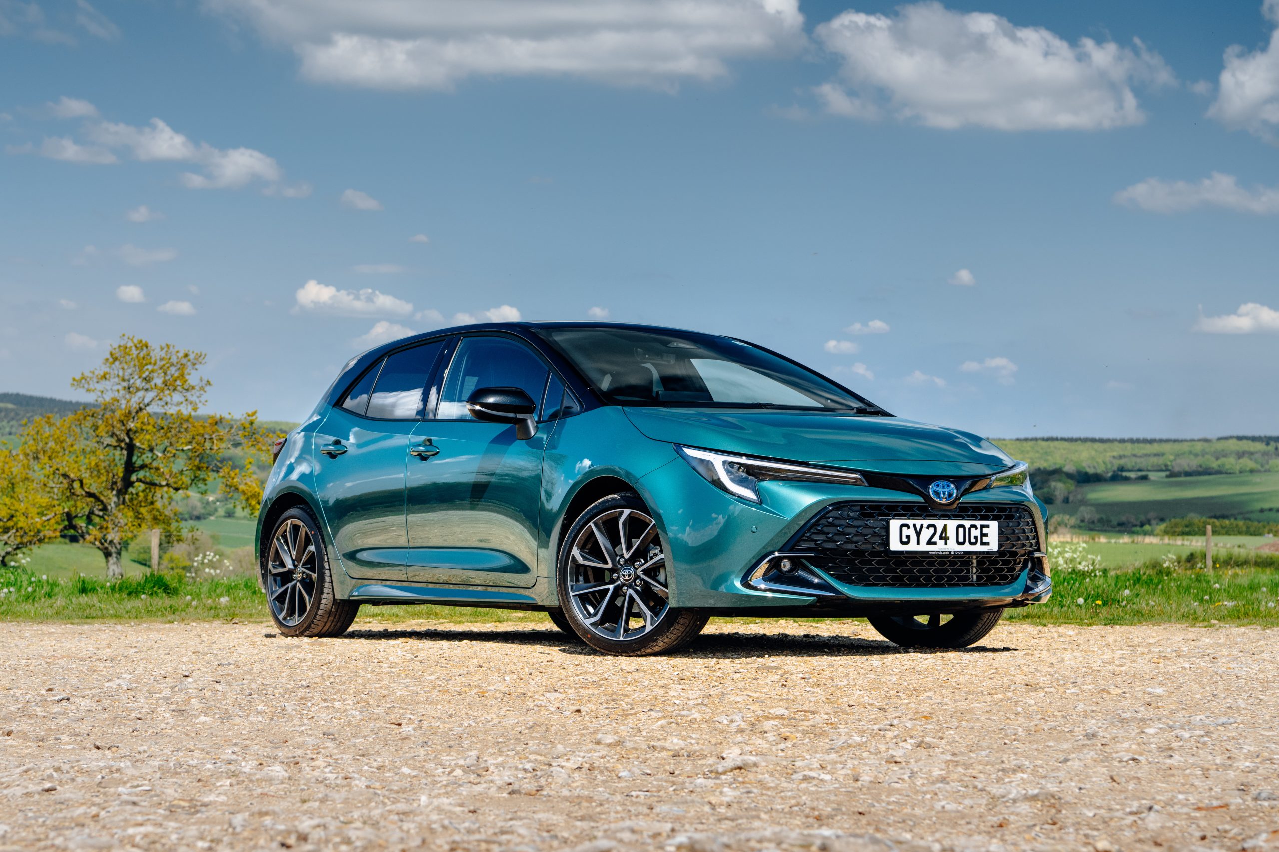 Green Toyota Corolla hatchback parked in the countryside