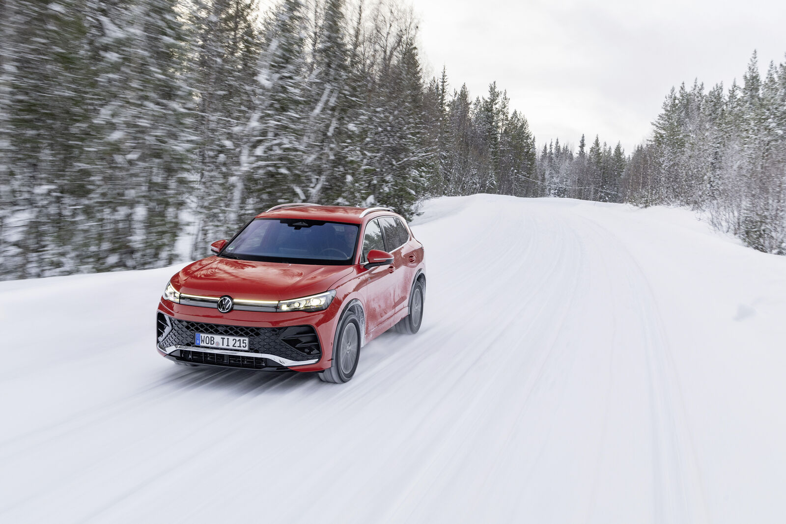 Blue Volkswagen Tiguan driving through snow, a compact SUV class example